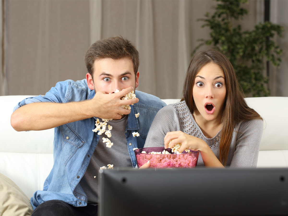 Couple eating popcorn while watching TV
