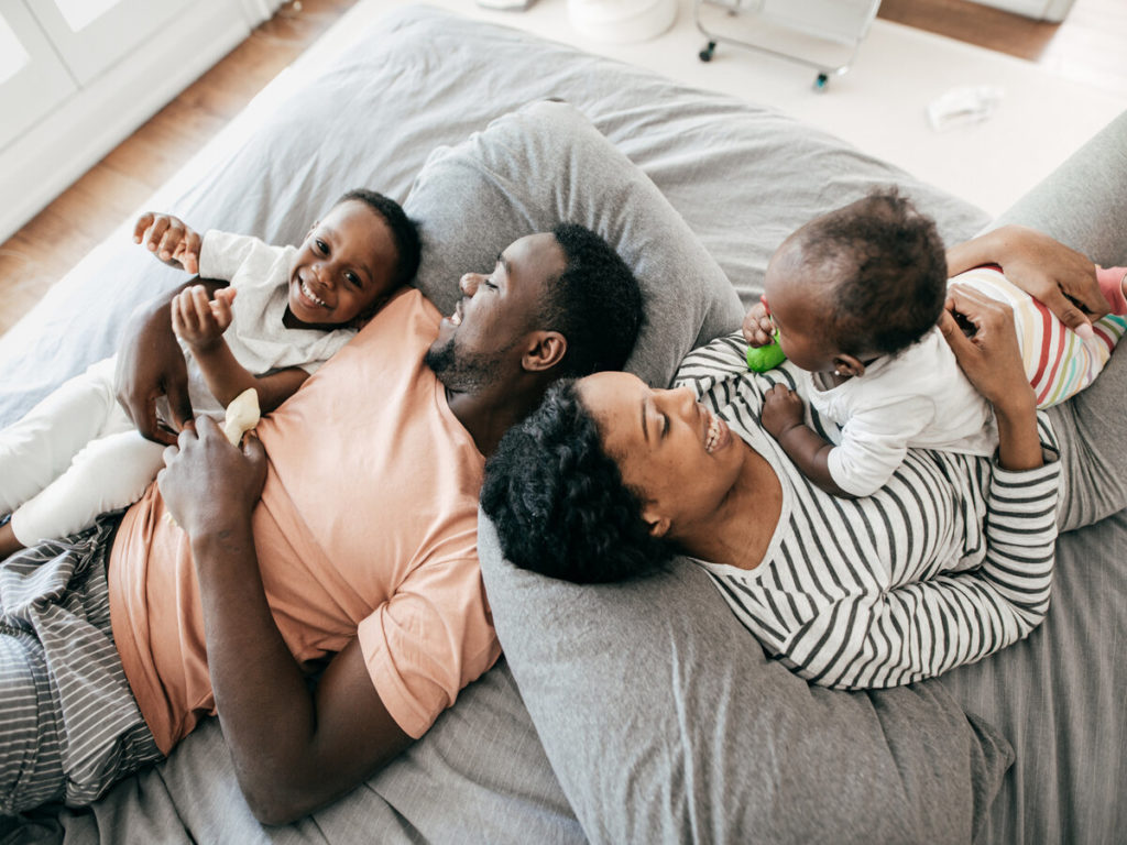 Happy family with two kids laying in bed together
