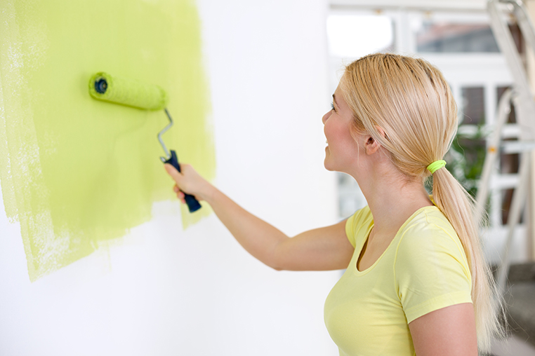 Young woman painting wall