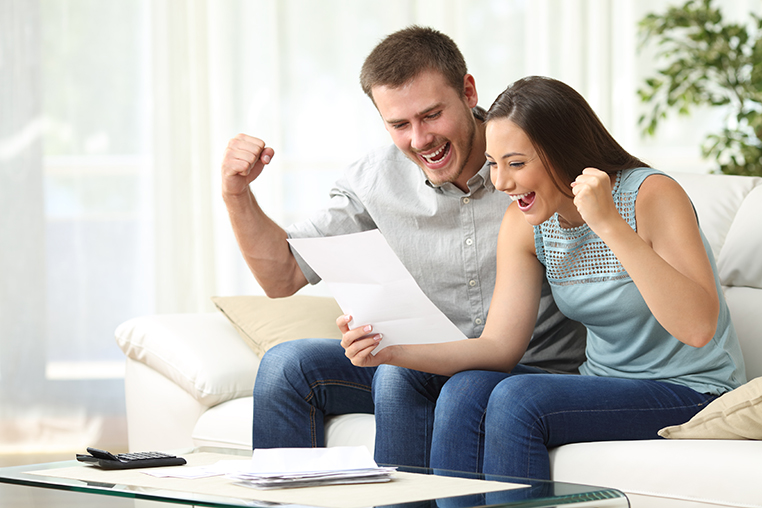 Excited couple reading a letter at home