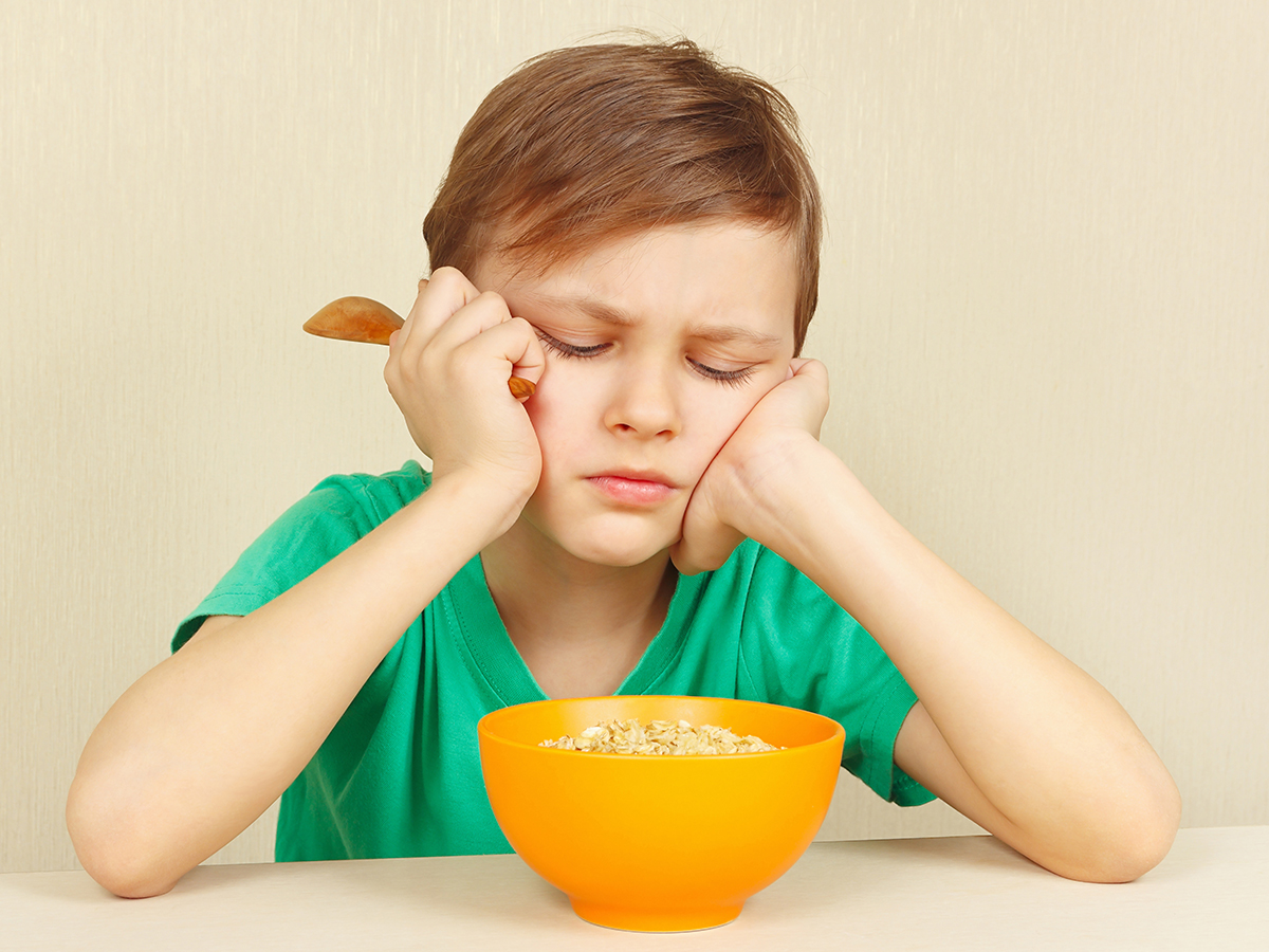 Unhappy kid with a bowl of cereal