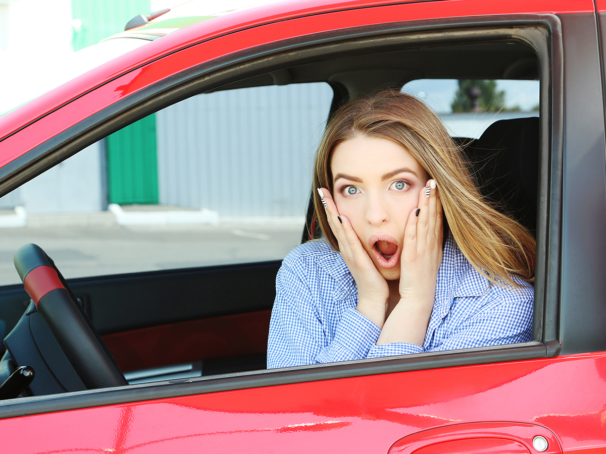Shocked woman looking out of her car window