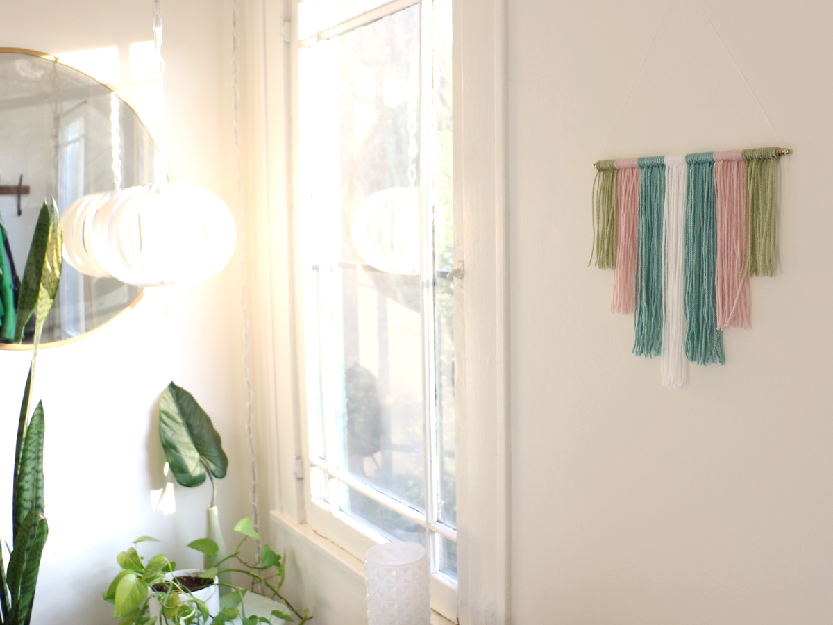 DIY yarn wall art hanging in a bedroom