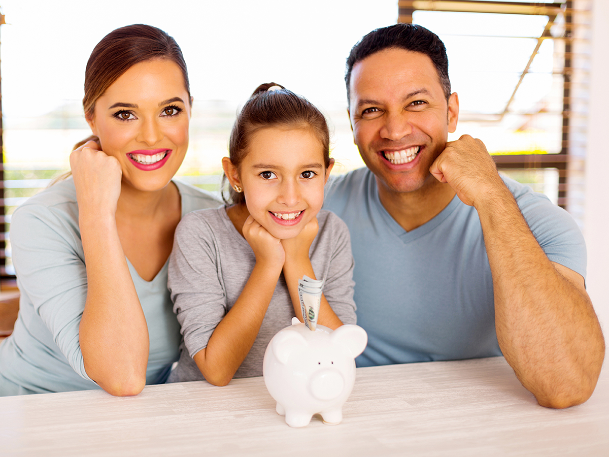 Cheerful family of three with piggybank at home