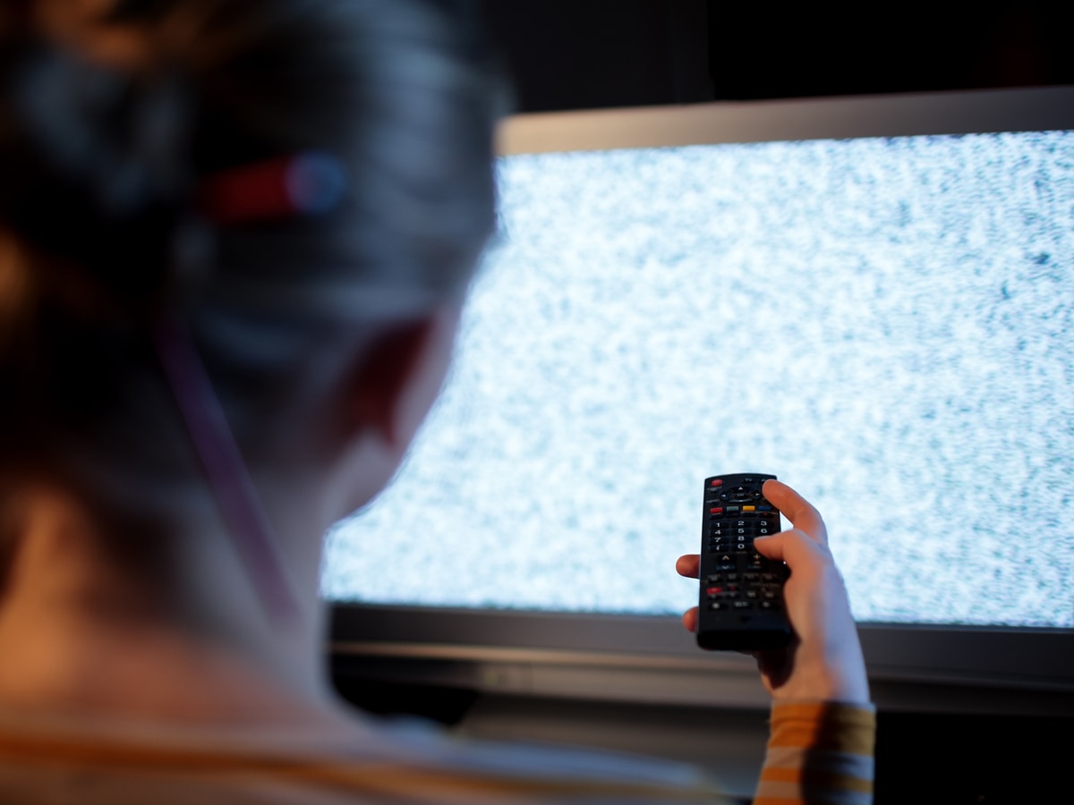 Woman flipping through channels on static-covered TV screen 