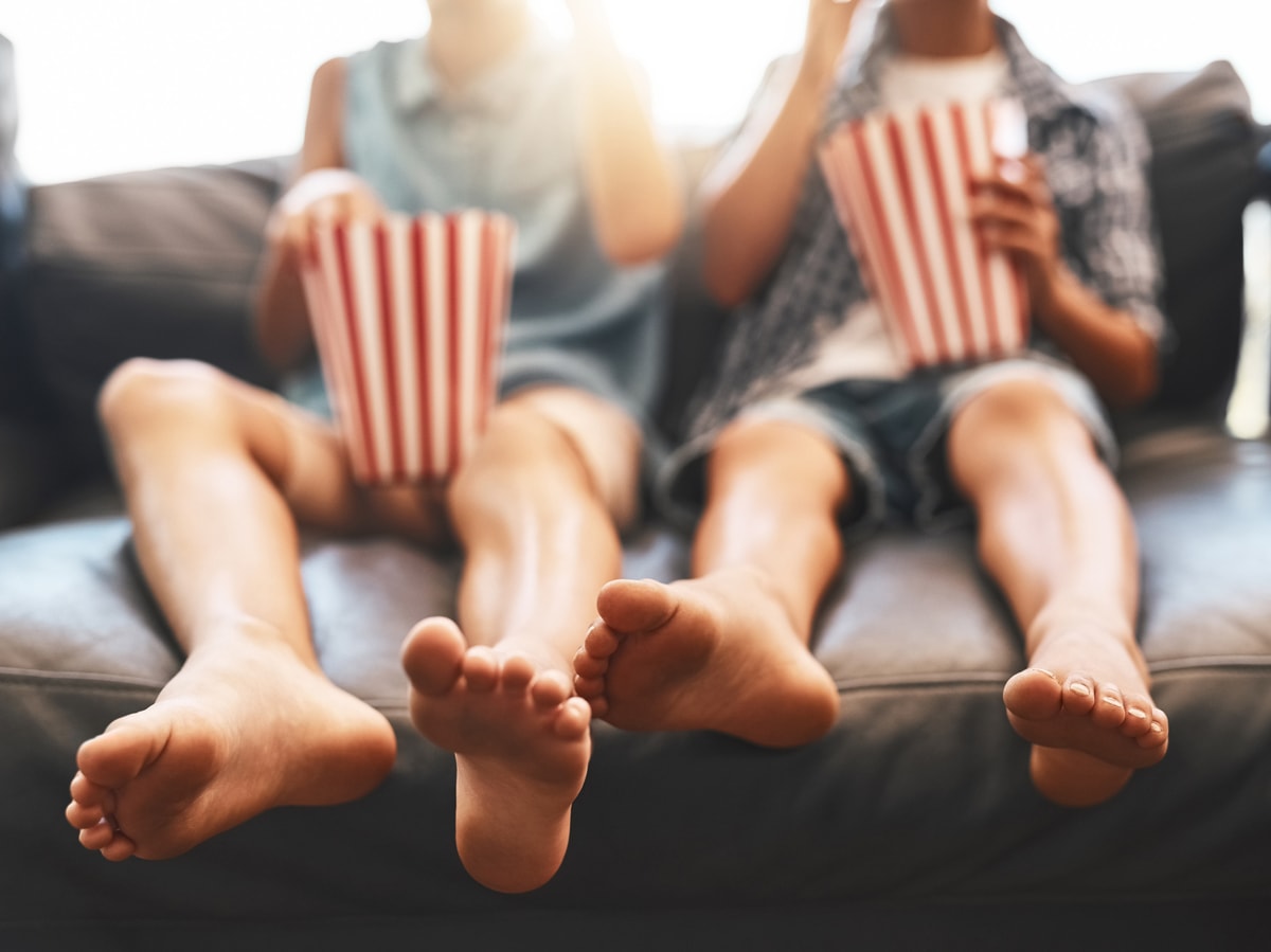 man and woman sitting next to each other on sectional while eating popcorn