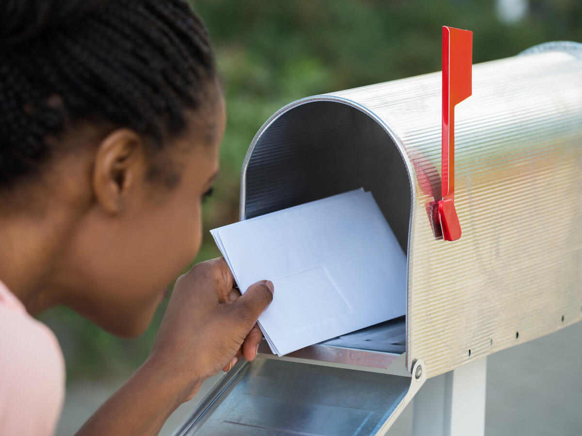 Woman getting mail out of new silver mailbox with red flag up
