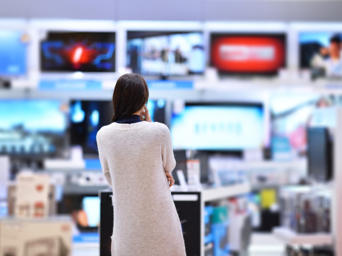 Woman contemplating over a new TV in an electronics store