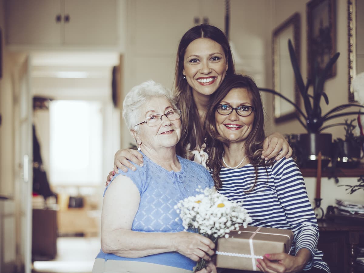 Three generations of women smiling at camera.