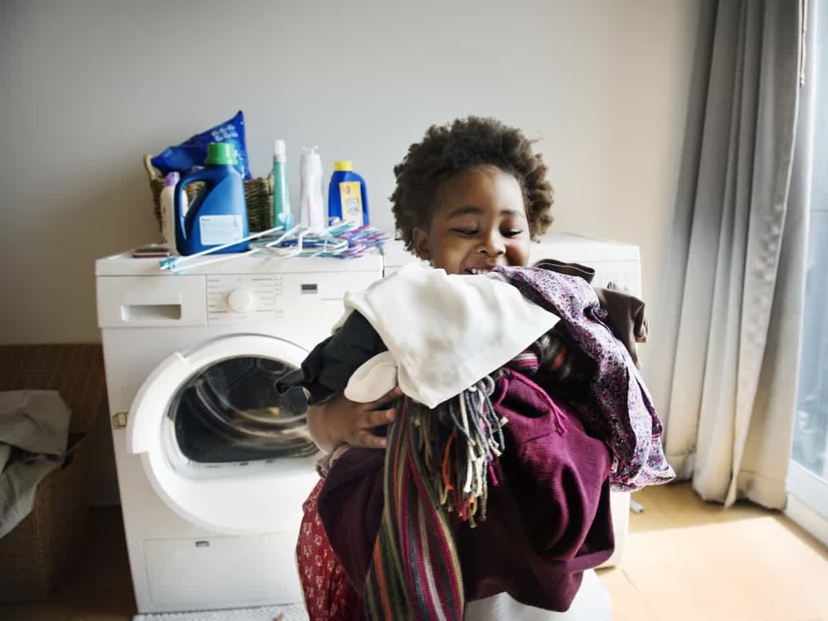 Child carrying laundry from dryer.