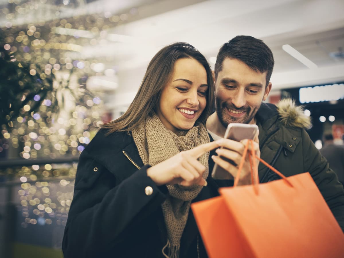 Couple in mall during holidays looking at smartphone