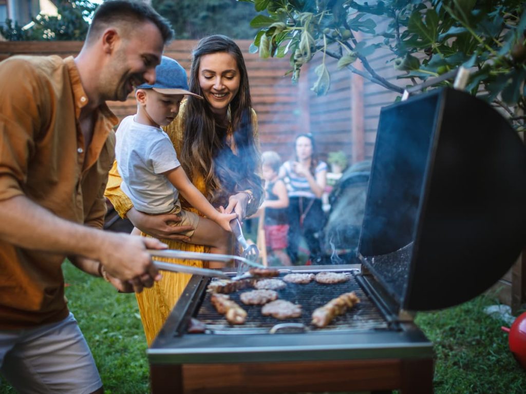 Backyard party with male cooking meat on grill
