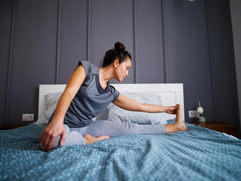 Woman with high bun stretching in bed
