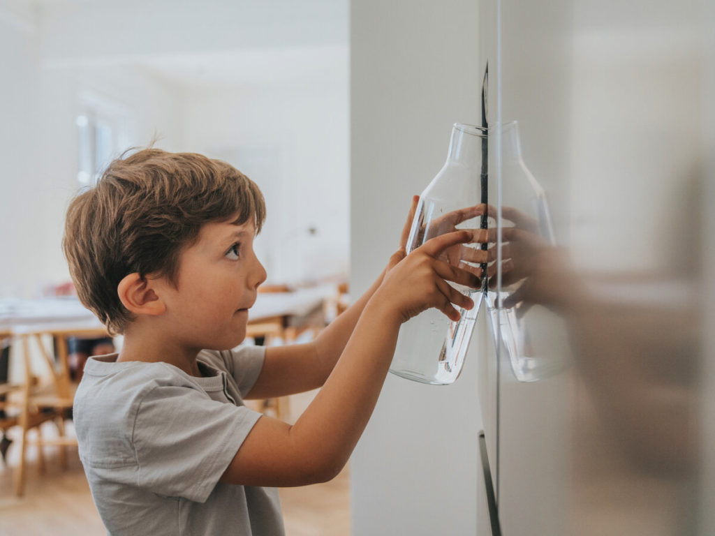 Boy filling glass with water and ice from Refrigerator