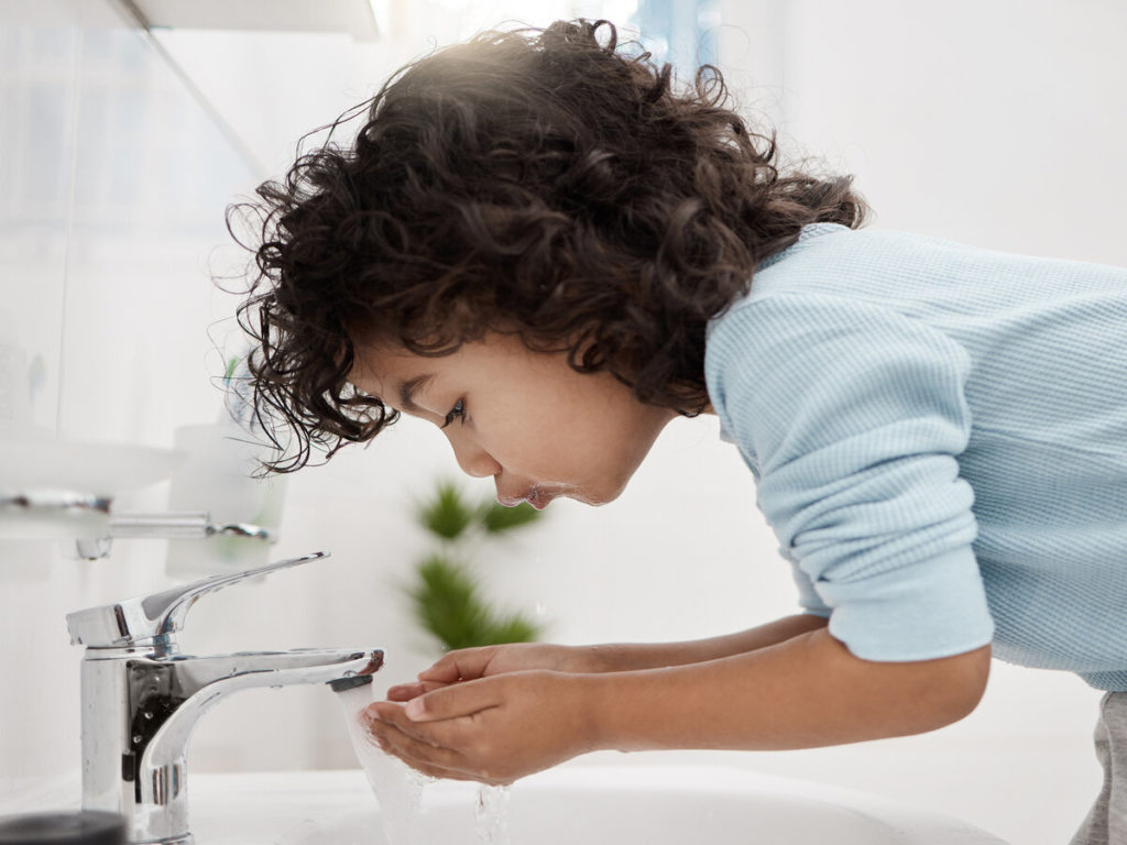 Shot of an adorable little boy attempting to drink water in a bathroom at home
