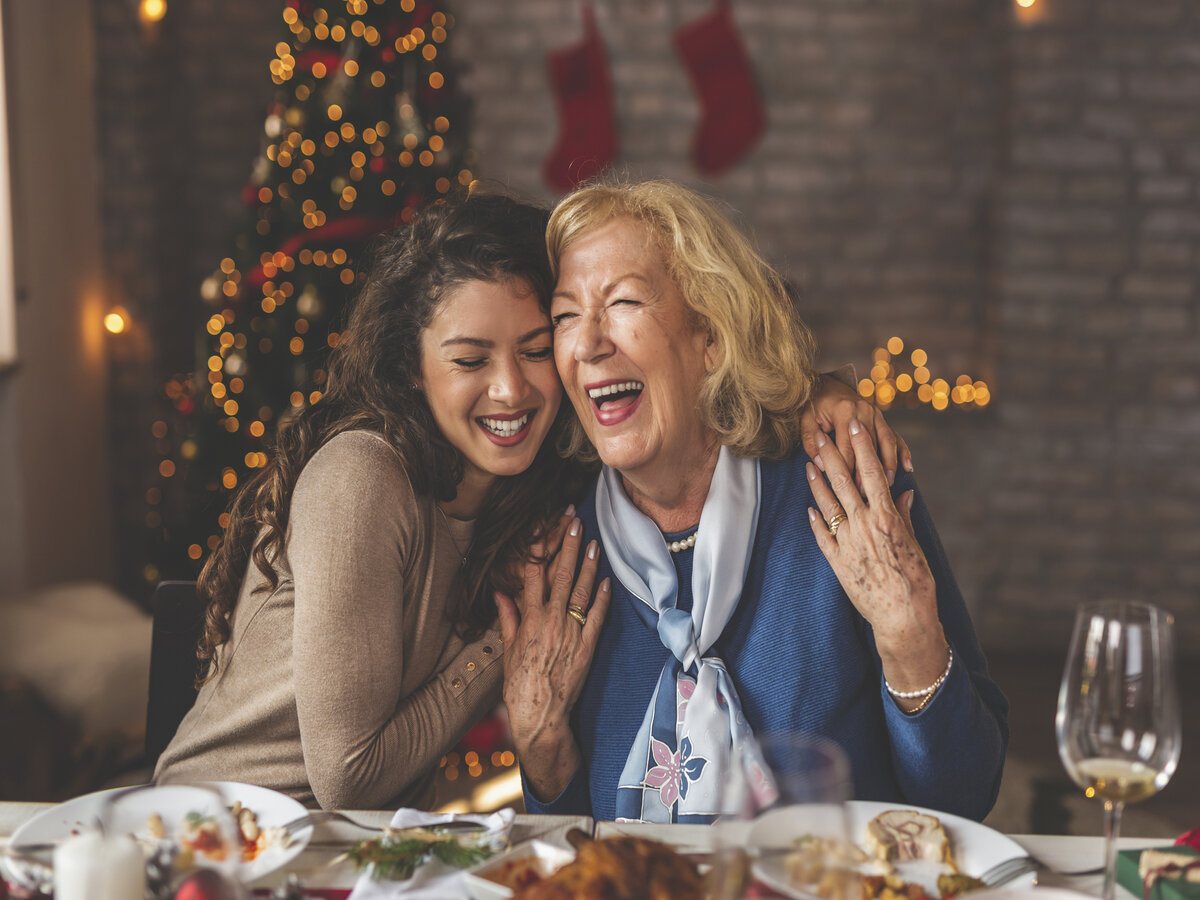 Daughter hugging her mother and smiling at Christmas dinner table