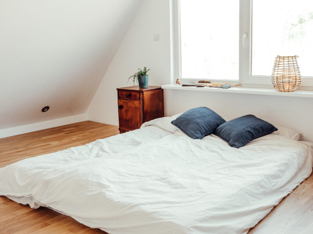 Lone mattress on bedroom floor with two pillows near window
