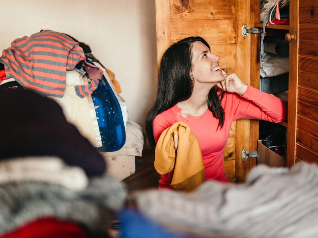 Woman sitting on floor in bedroom organizing closet