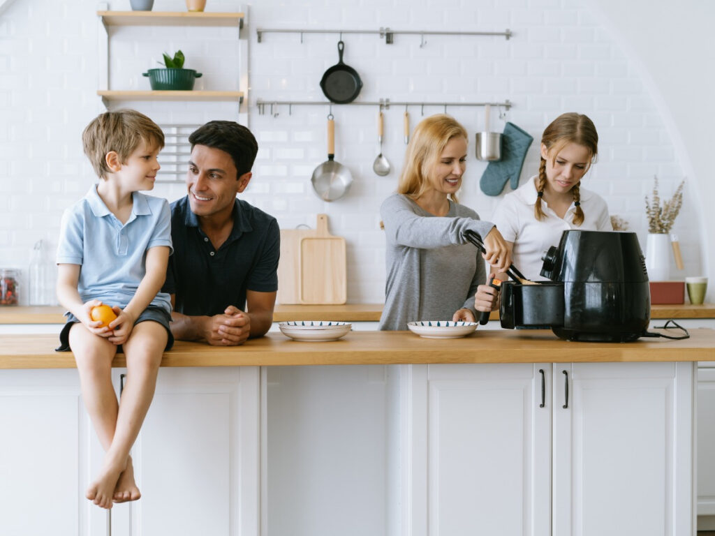 Family of four (mom, dad, son, and daughter) in kitchen while air frying food