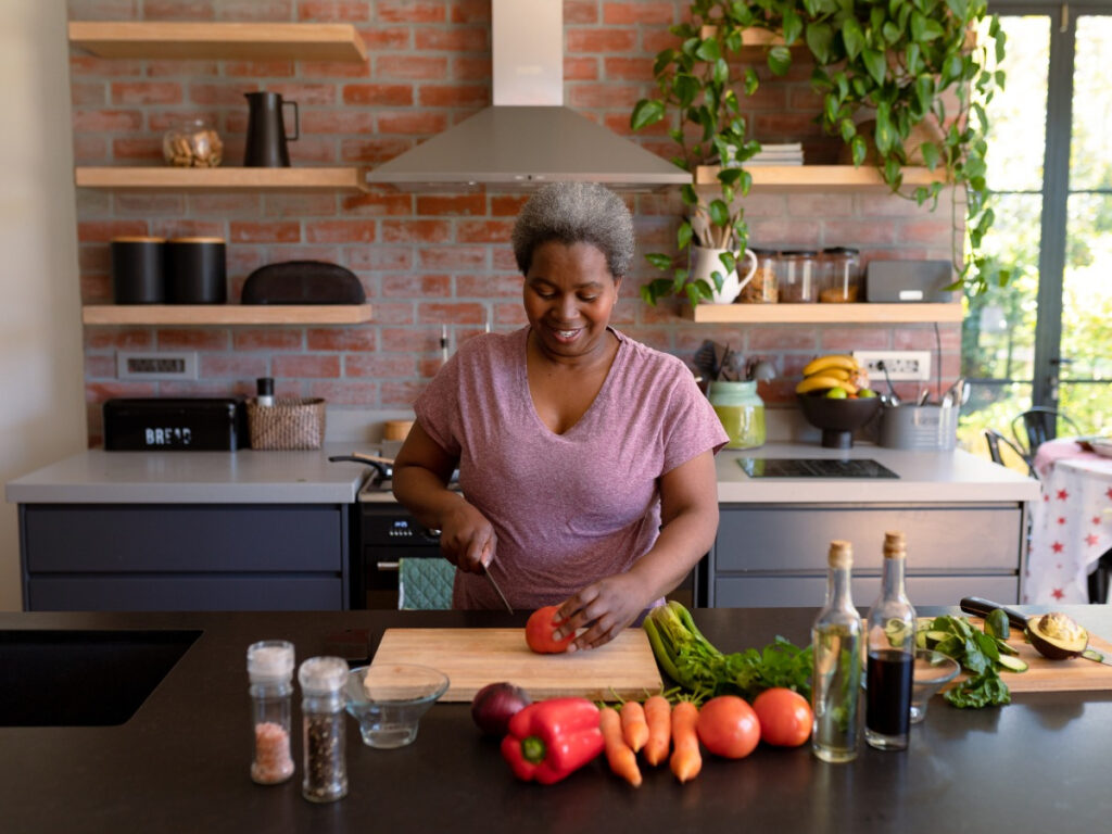 Woman in beautiful kitchen with plants chopping vegetables