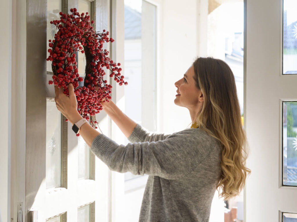 Woman hanging fall wreathe on front door