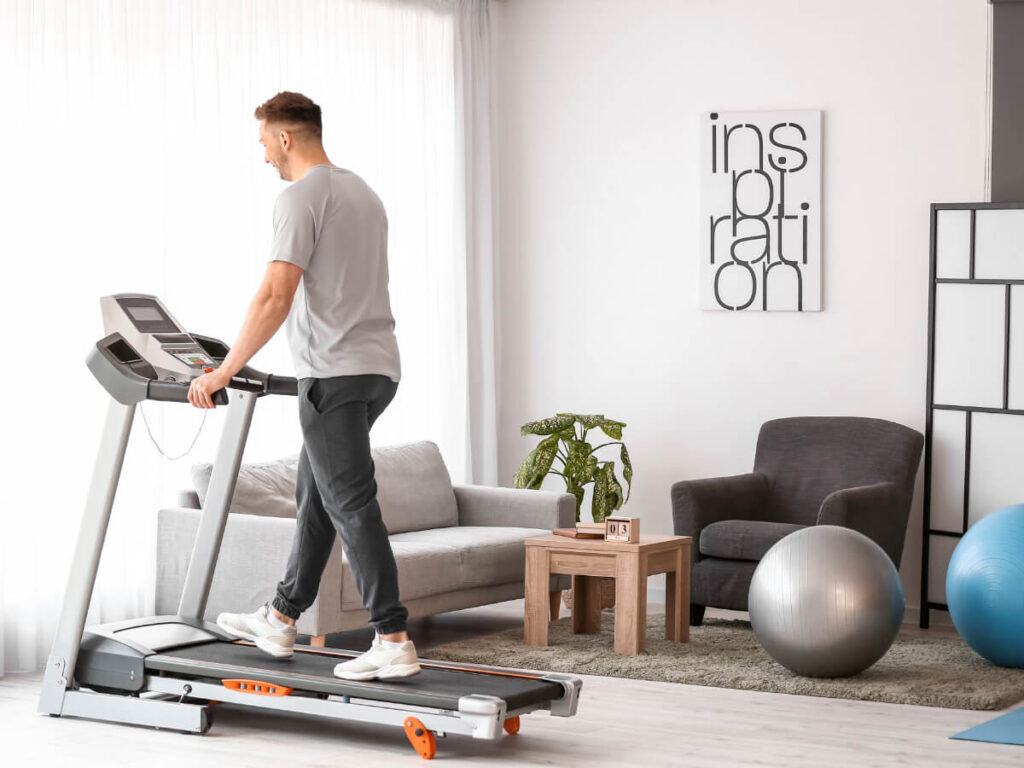 Man walking on a treadmill inside of his living room at home