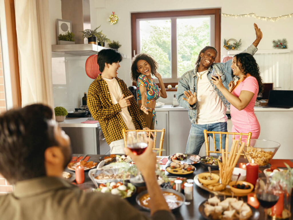 Group of diverse friends smiling and dancing in a kitchen