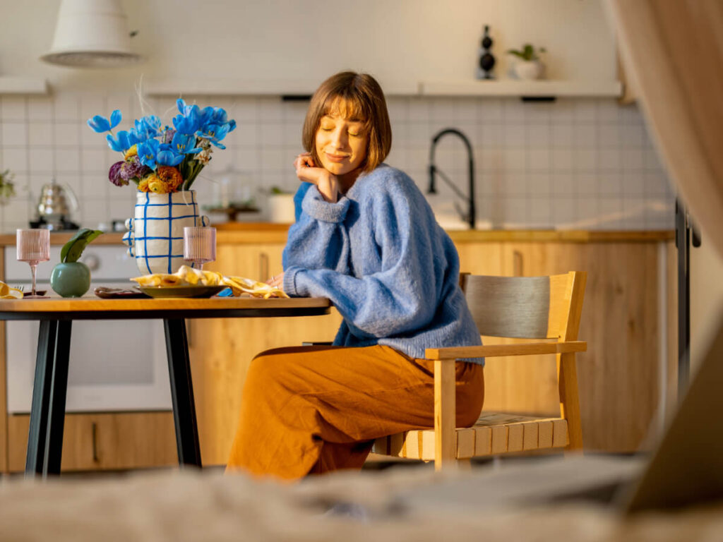 Woman sitting at dining room table with a pleasant smile and sunny environment