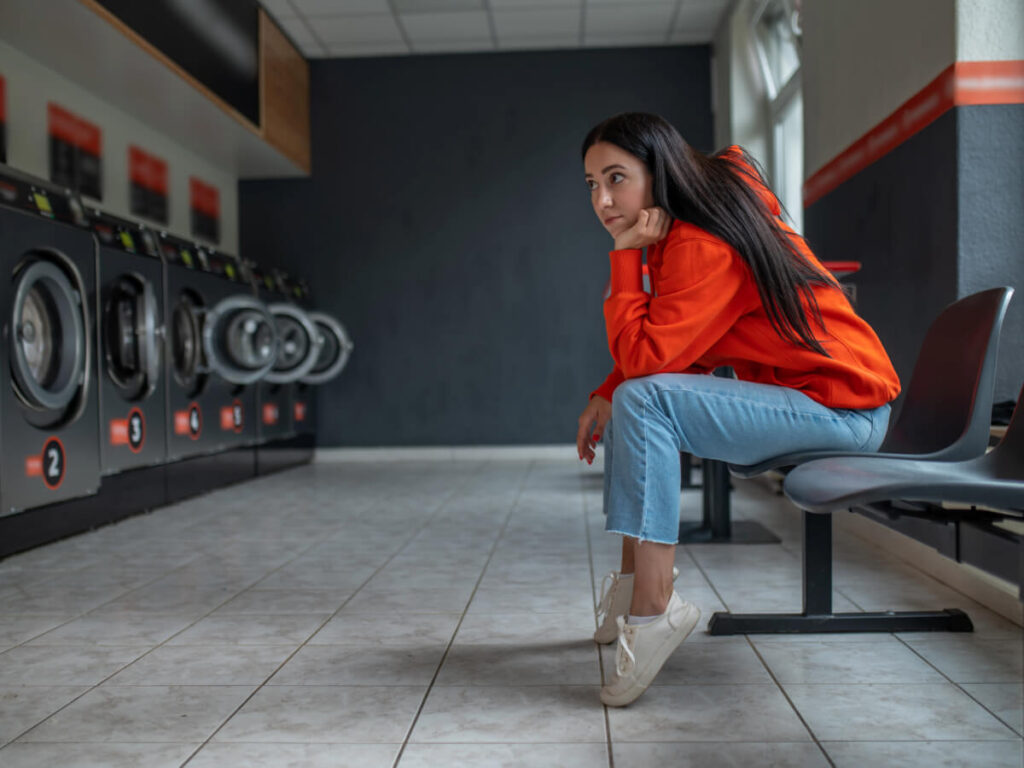 Woman sitting solemnly in a laundromat resting her chin on her fist