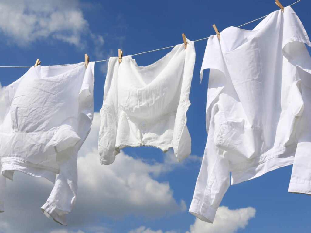 White clothing hanging on a dryer line with a beautiful blue sky backdrop