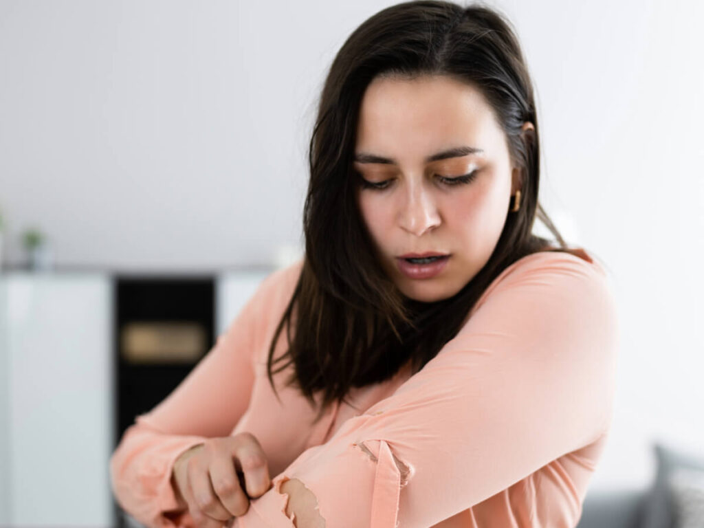 Woman looking at hole in the sleeve of her shirt