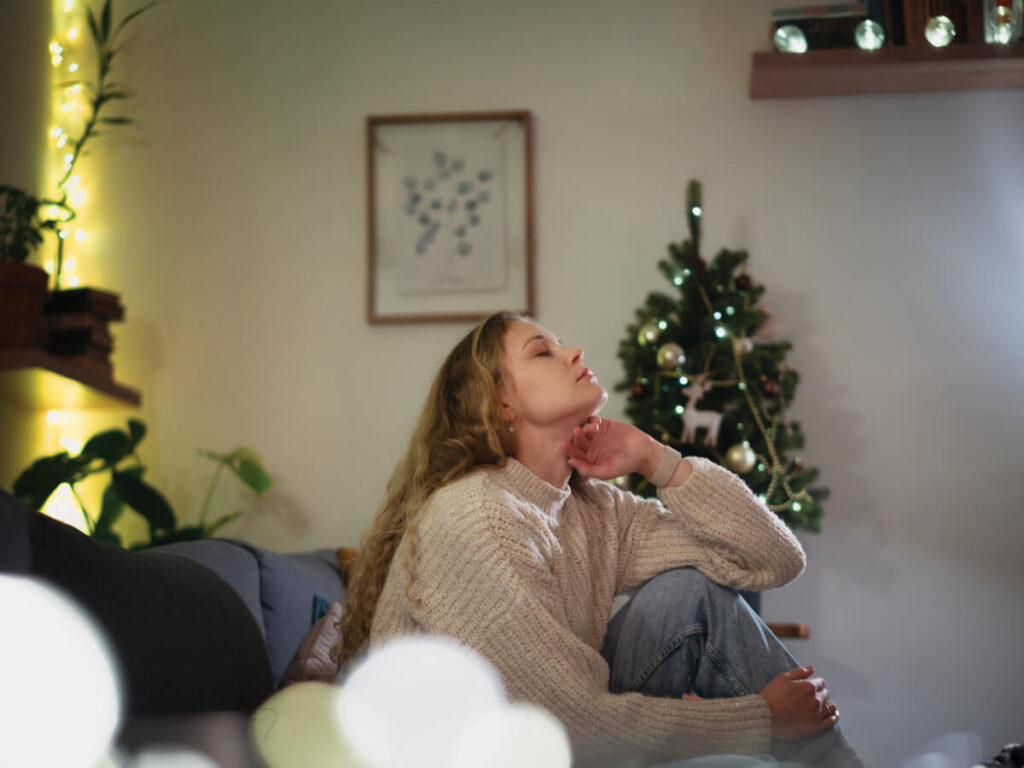 Woman looking distraught on sofa with Christmas tree in background