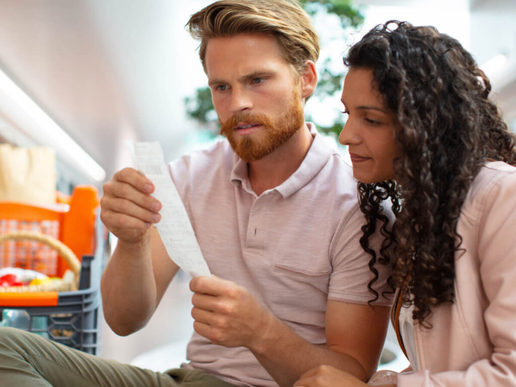 Frustrated and concerned couple looking at grocery store receipt