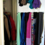Scarves and hats hanging on the inside of a closet door.