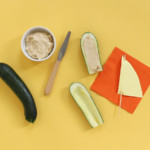 Once your sails are ready, slice zucchini in half, hollow it out, and fill with hummus.