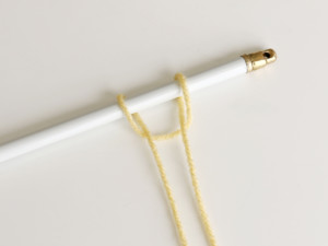 Bring the two ends through the center loop of the yarn, with the hanging rod positioned inside the loop.