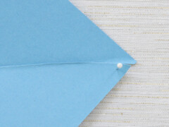 Take a sewing pin and gently make a hole through the center of the paper (where the creases meet), as well as at every other corner tab.