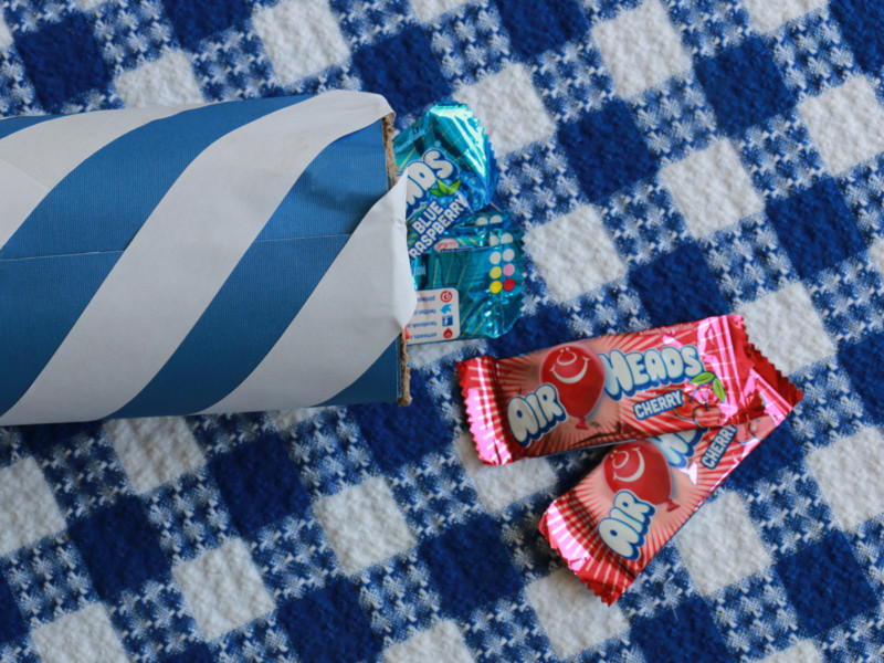 At the open end, fill the tube with candy. Candy coming out of striped paper tube
