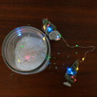 Miniature christmas trees sitting next to an open mason jar