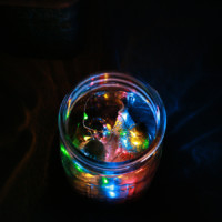 Top angled view of miniature christmas trees and string lights in a mason jar