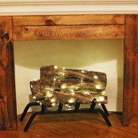 Twinkle lights wrapped around logs in a fireplace