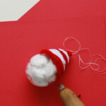 Continue wrapping until you’ve formed a hat shape, then use a dab of hot glue (on a low heat setting) to secure the end of the pipe cleaners to the ornament.