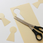 Scissors on paper with keyhole-shaped cutouts